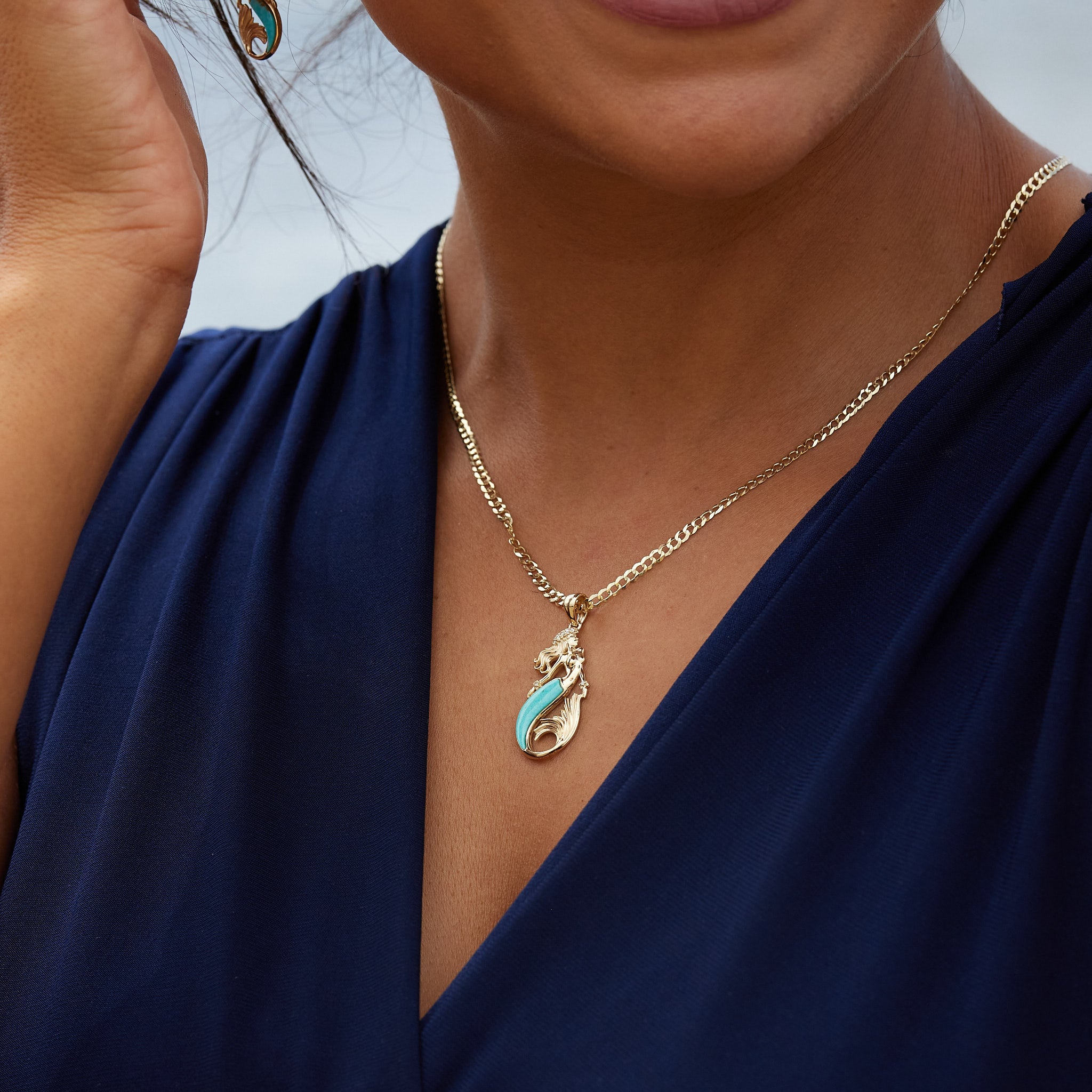 A woman's chest with a Sealife Mermaid Turquoise Pendant in Gold with Diamonds - 30mm - Maui Divers Jewelry