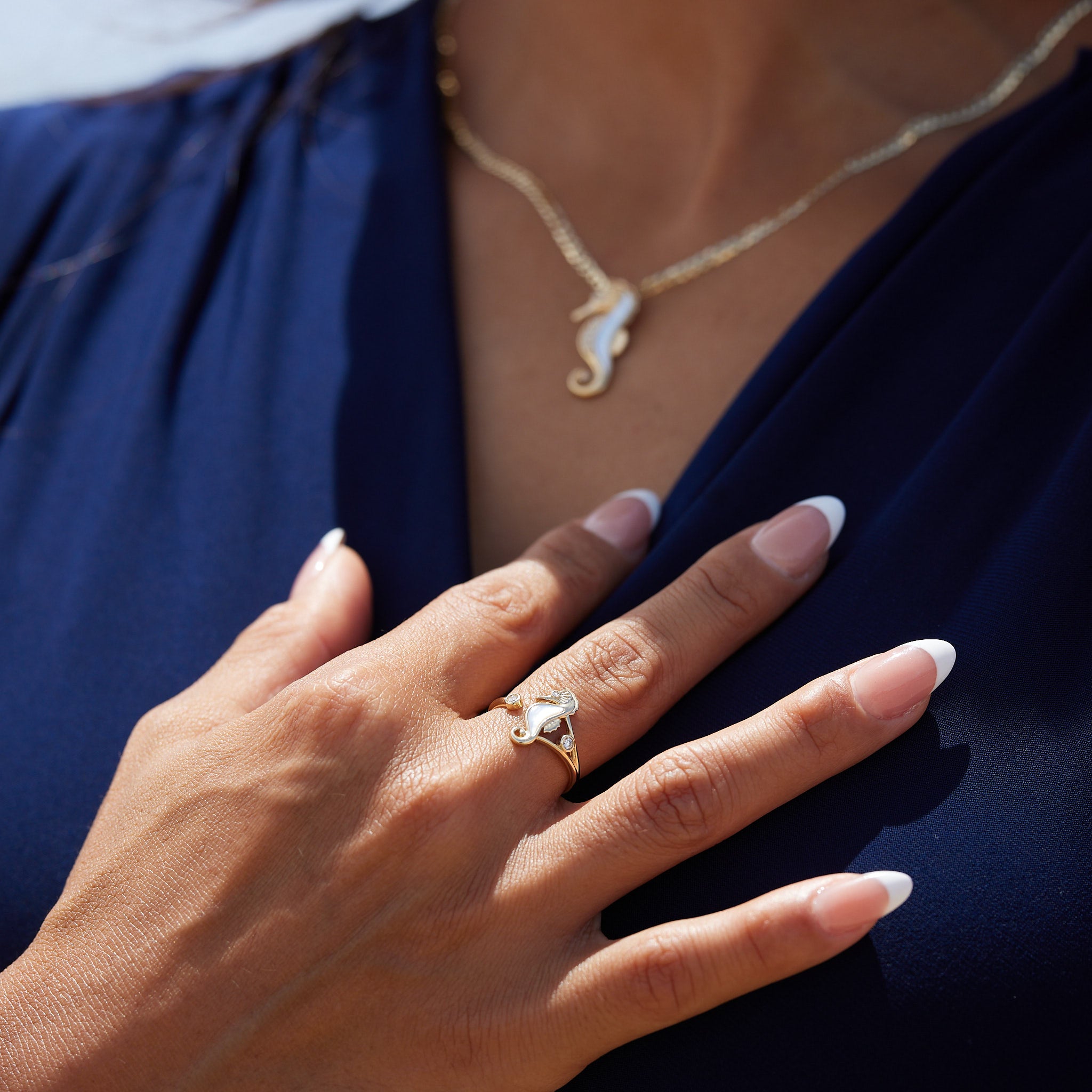 A woman's hand wearing a Sealife Seahorse Mother of Pearl Ring in Gold with Diamonds - 15mm - Maui Divers Jewelry