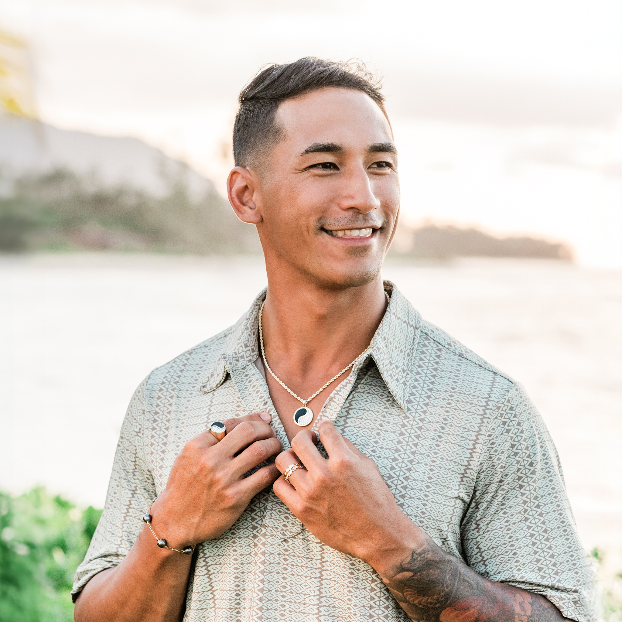 Man with a blurred beach background wearing 3mm Rope Chain in Gold and a Yin Yang Black Coral Pendant