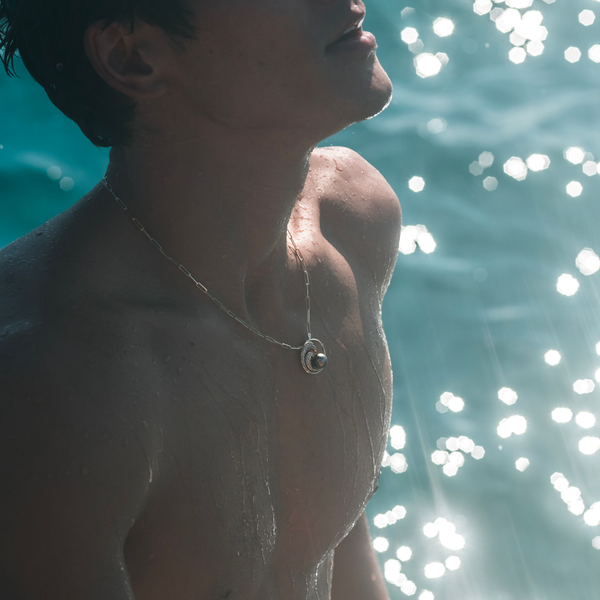 Man in the ocean wearing 2.7mm Paperclip Chain in 14k Yellow Gold with a Nalu pendant
