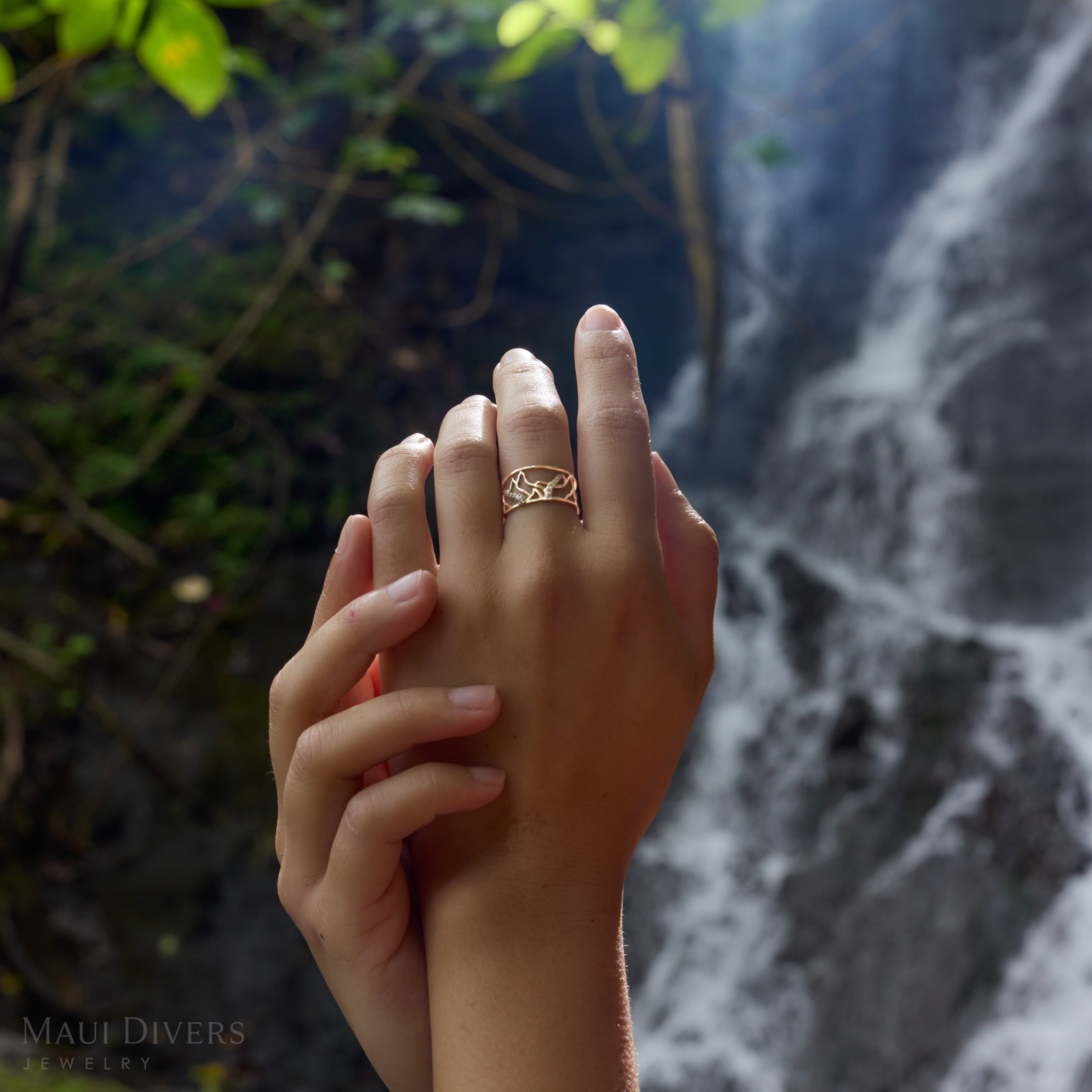 10mm Koʻolau Waterfall Ring in Gold with Diamonds on hands with a waterfall blurred in the background