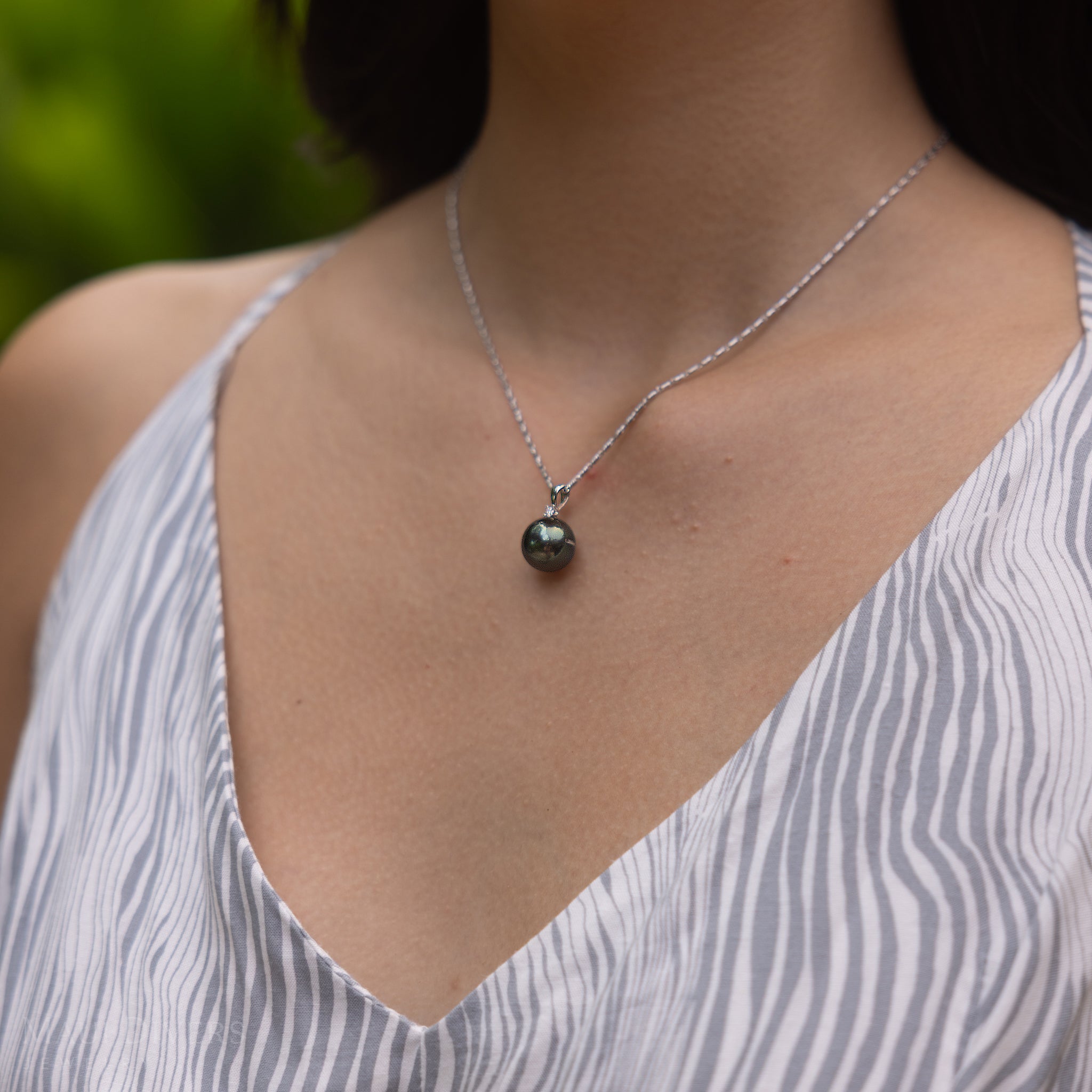 Close-up of a Tahitian black pearl pendant in white gold with diamond accent.