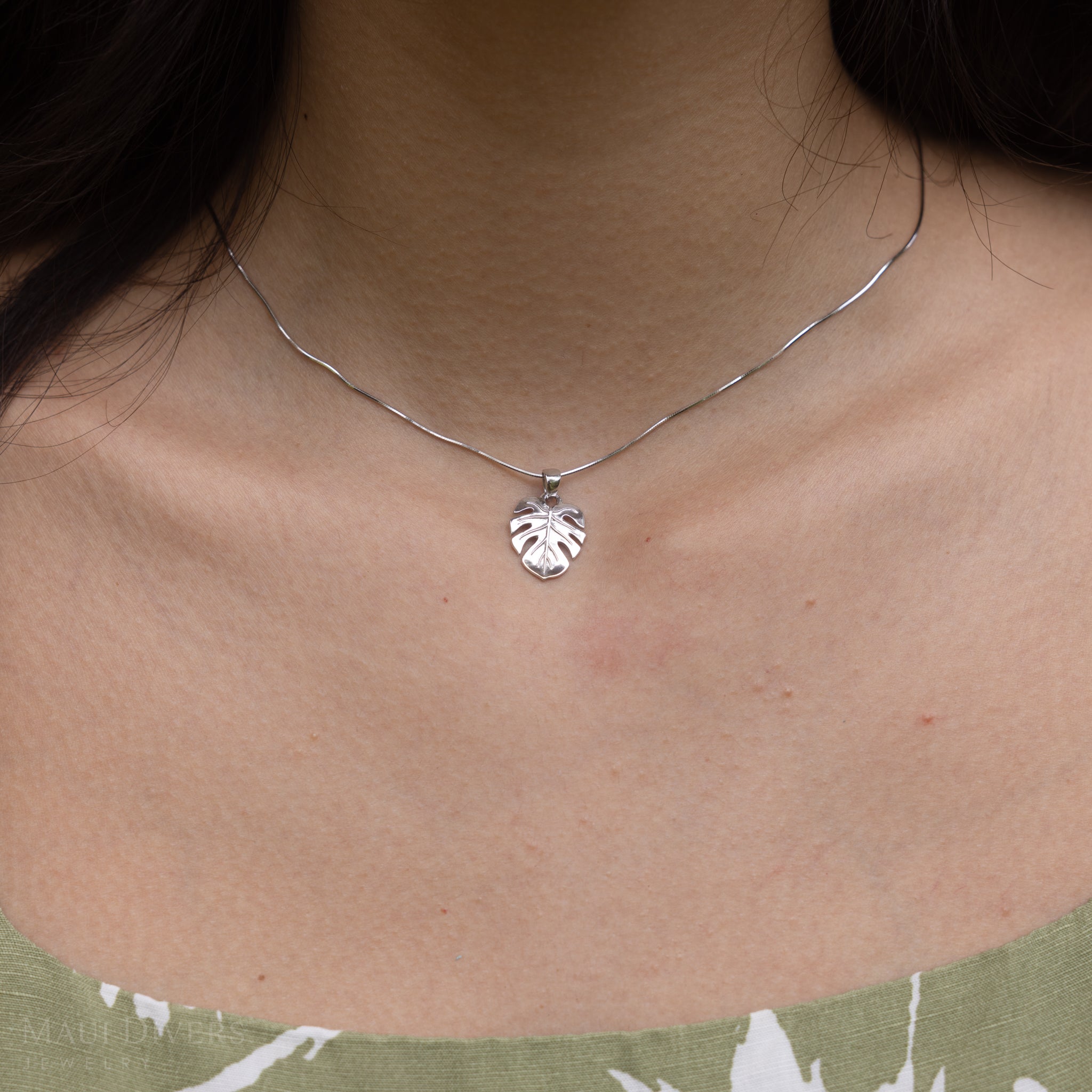 Close up of Monstera Pendant in Sterling Silver on a woman's neckline