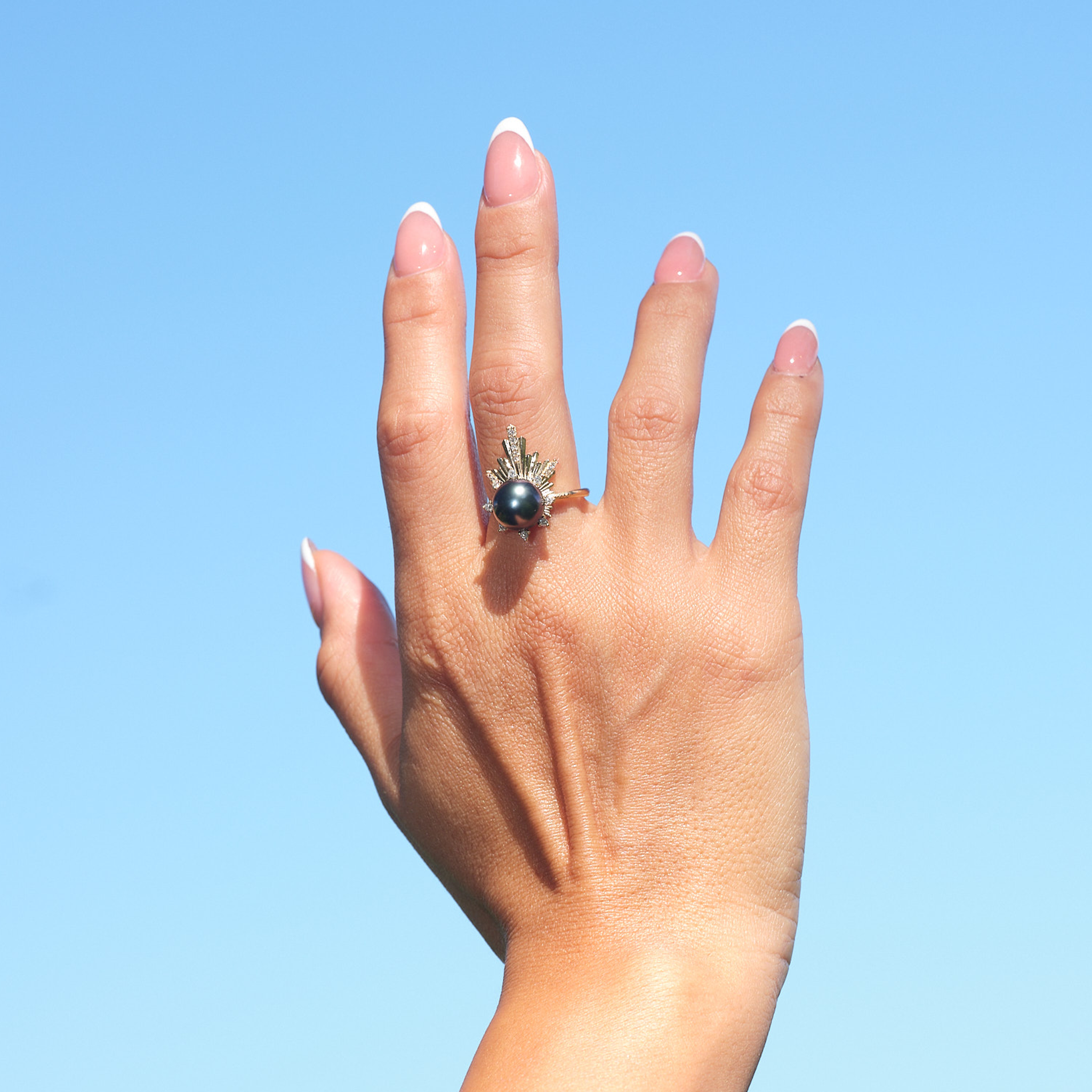 A woman's hand wearing a E Hoʻāla Tahitian Black Pearl Ring in Gold with Diamonds - 21mm - Maui Divers Jewelry