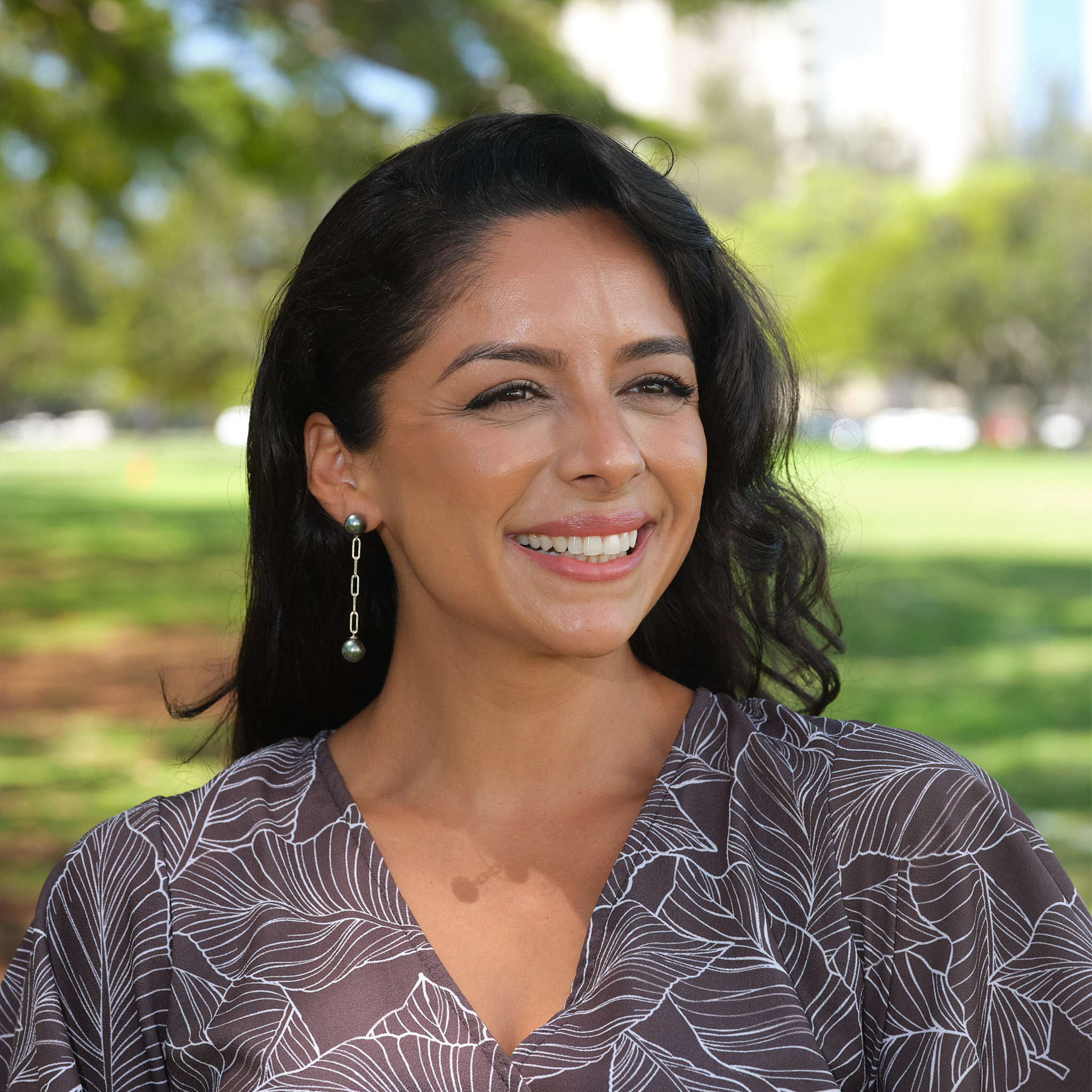 Woman in a park wearing 9-11mm Tahitian Black Pearl Paperclip Chain Earrings in 14k Yellow Gold