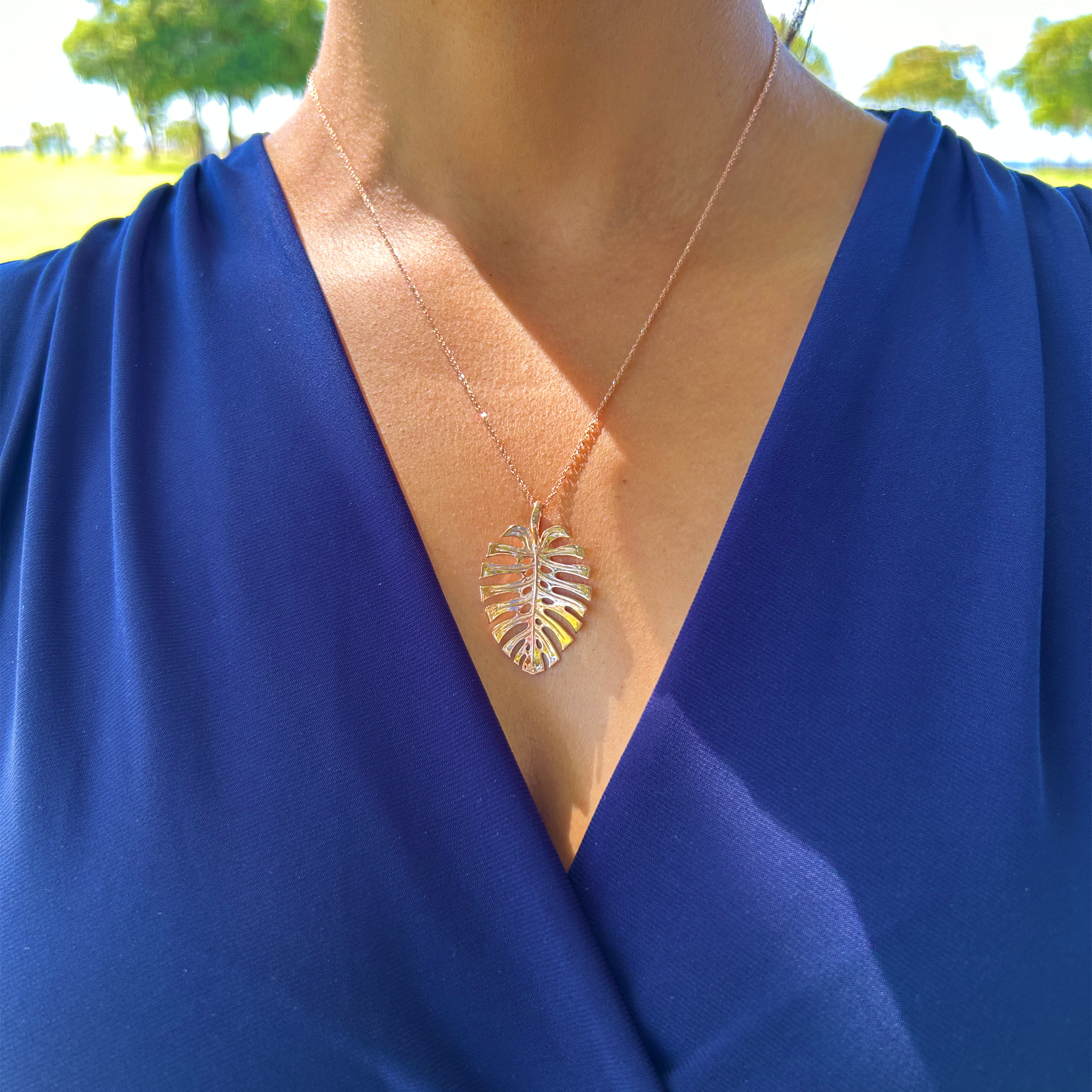 A woman wearing a 0.8mm Baby Rope Chain in Rose Gold with a Monstera pendant outdoors