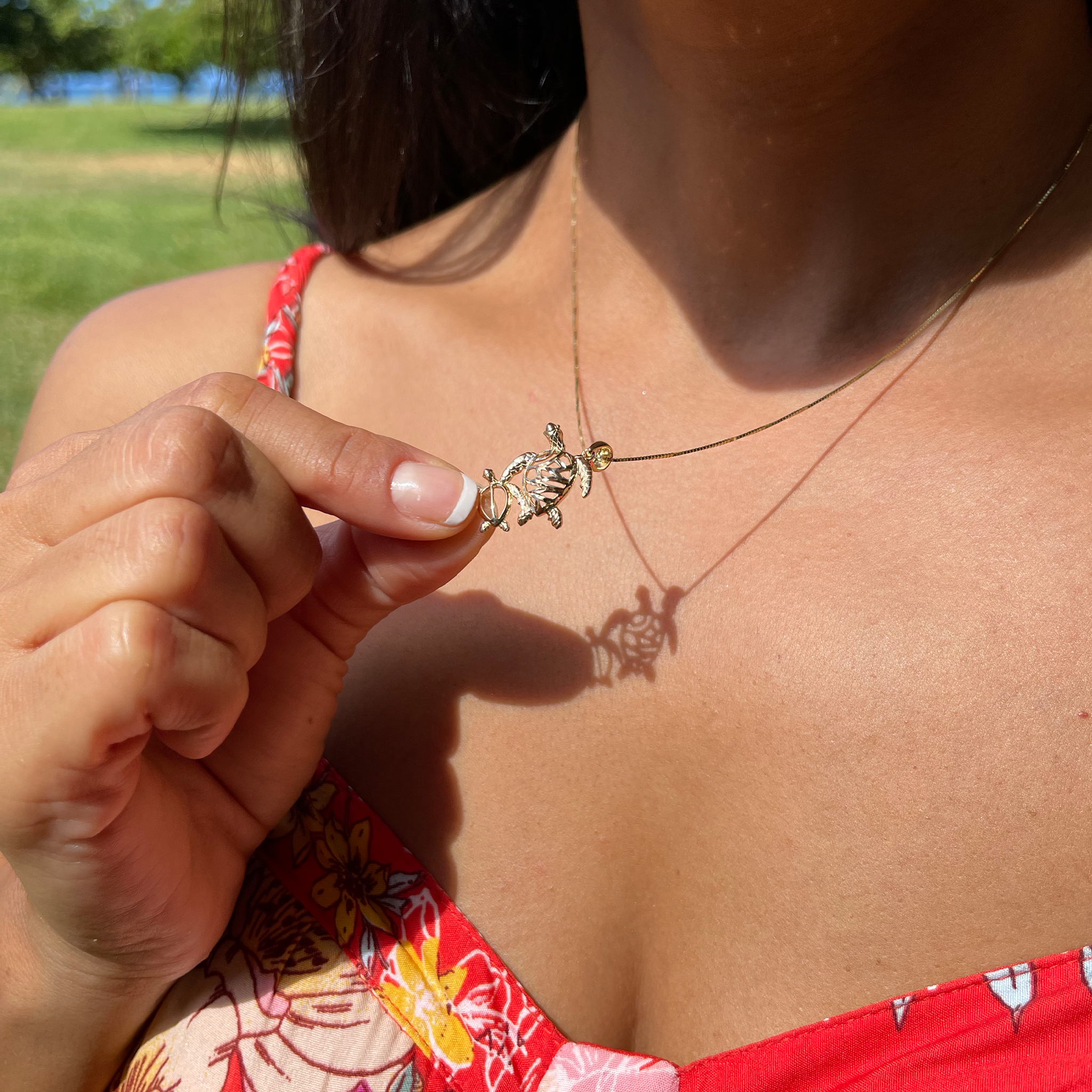 A woman holding a Honu Ohana Pendant in Gold - 19mm - Maui Divers Jewelry