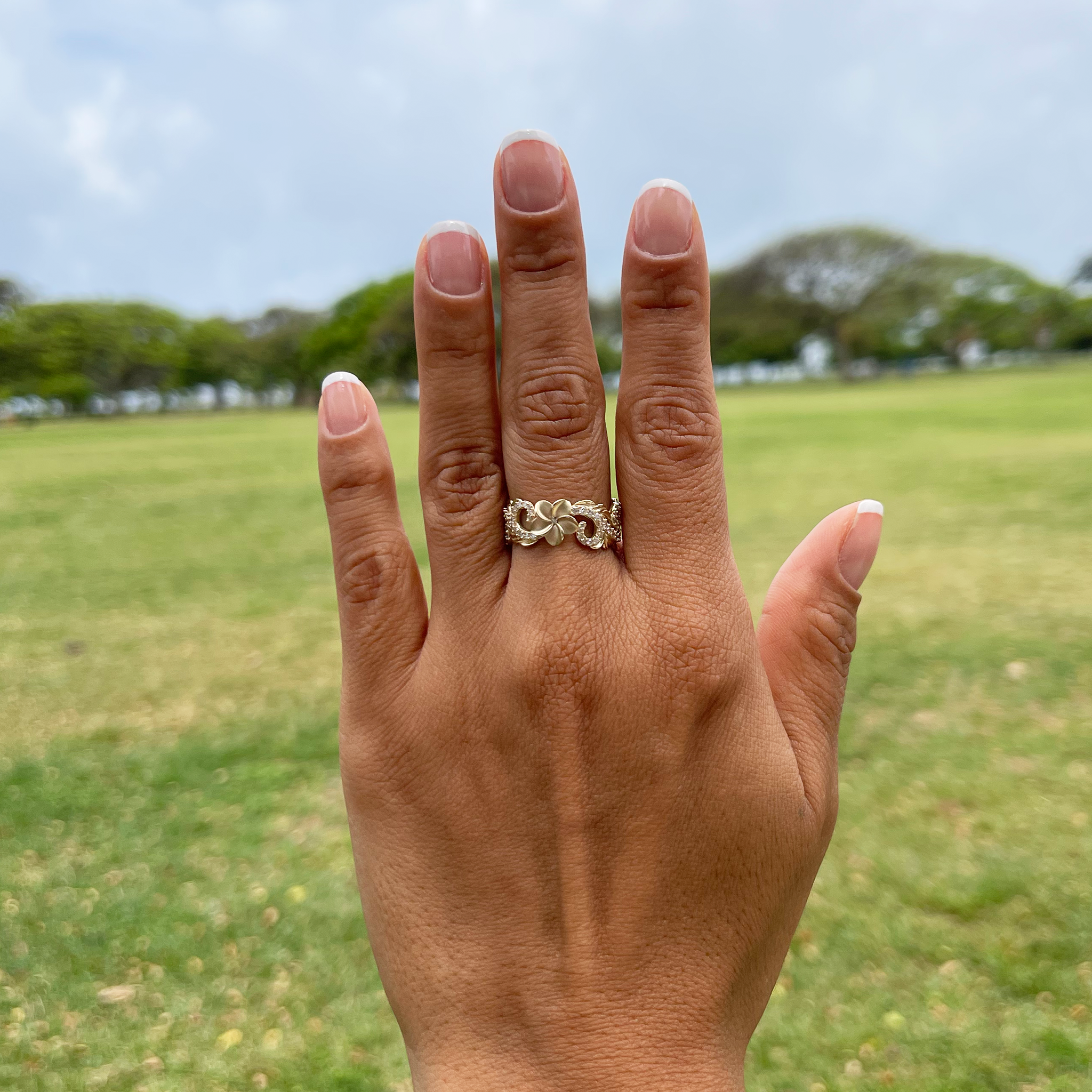 A woman's hand with a Hawaiian Heirloom Plumeria Ring in Gold with Diamonds - 8mm - Maui Divers Jewelry