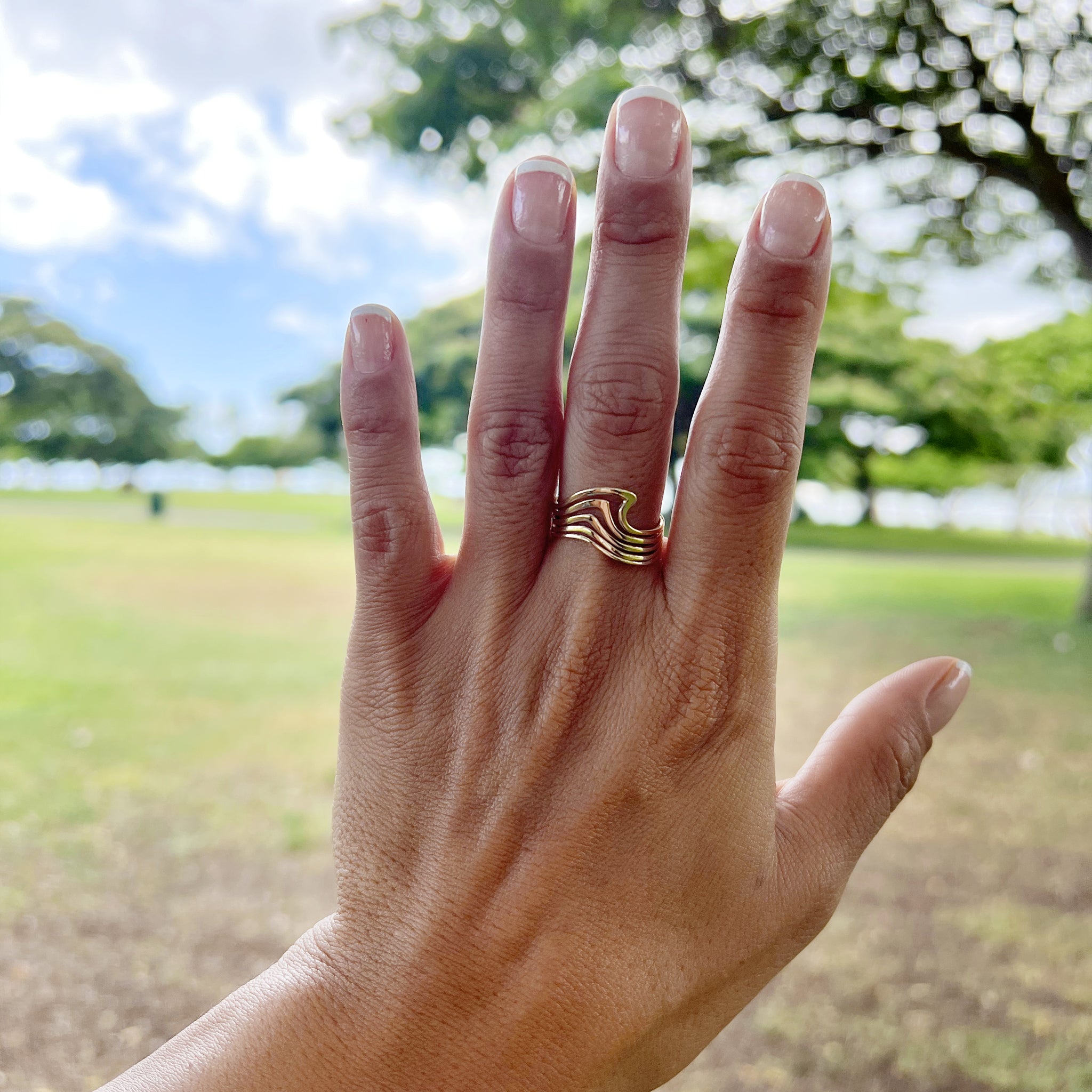 A woman's hand wearing a Nalu Ring in Gold - 11mm - Maui Divers Jewelry