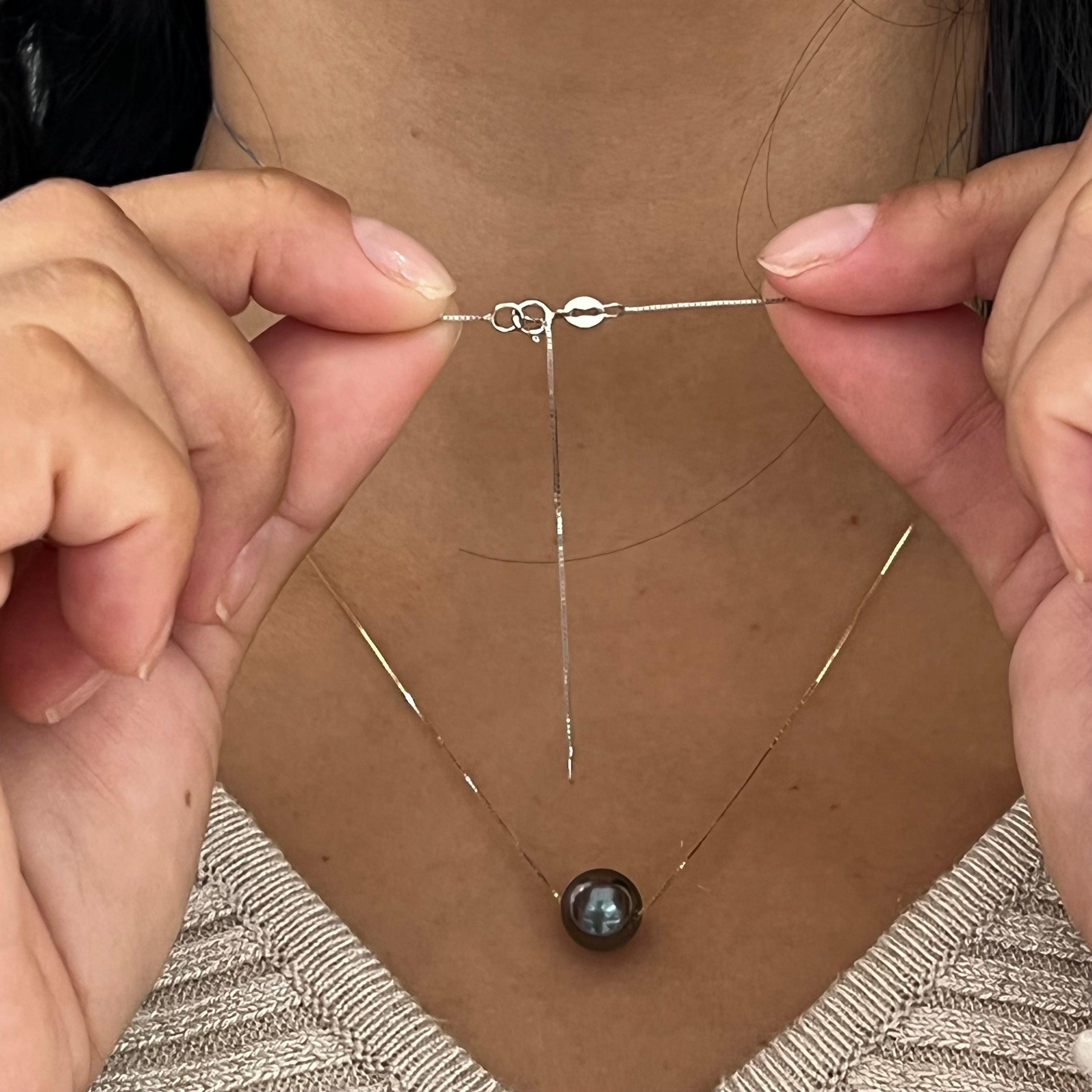 A woman showing the backing of the 16-18" Adjustable Tahitian Black Floating Pearl Necklace in White Gold-Maui Divers Jewelry