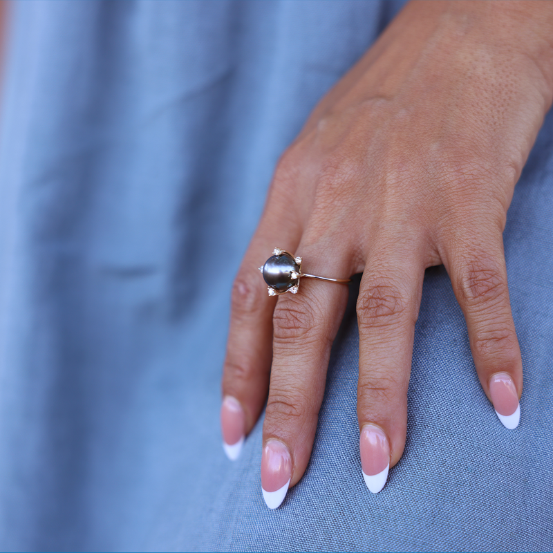 A woman's hand wearing a Protea Tahitian Black Pearl Ring in Gold with Diamonds (10-11mm)-Maui Divers Jewelry
