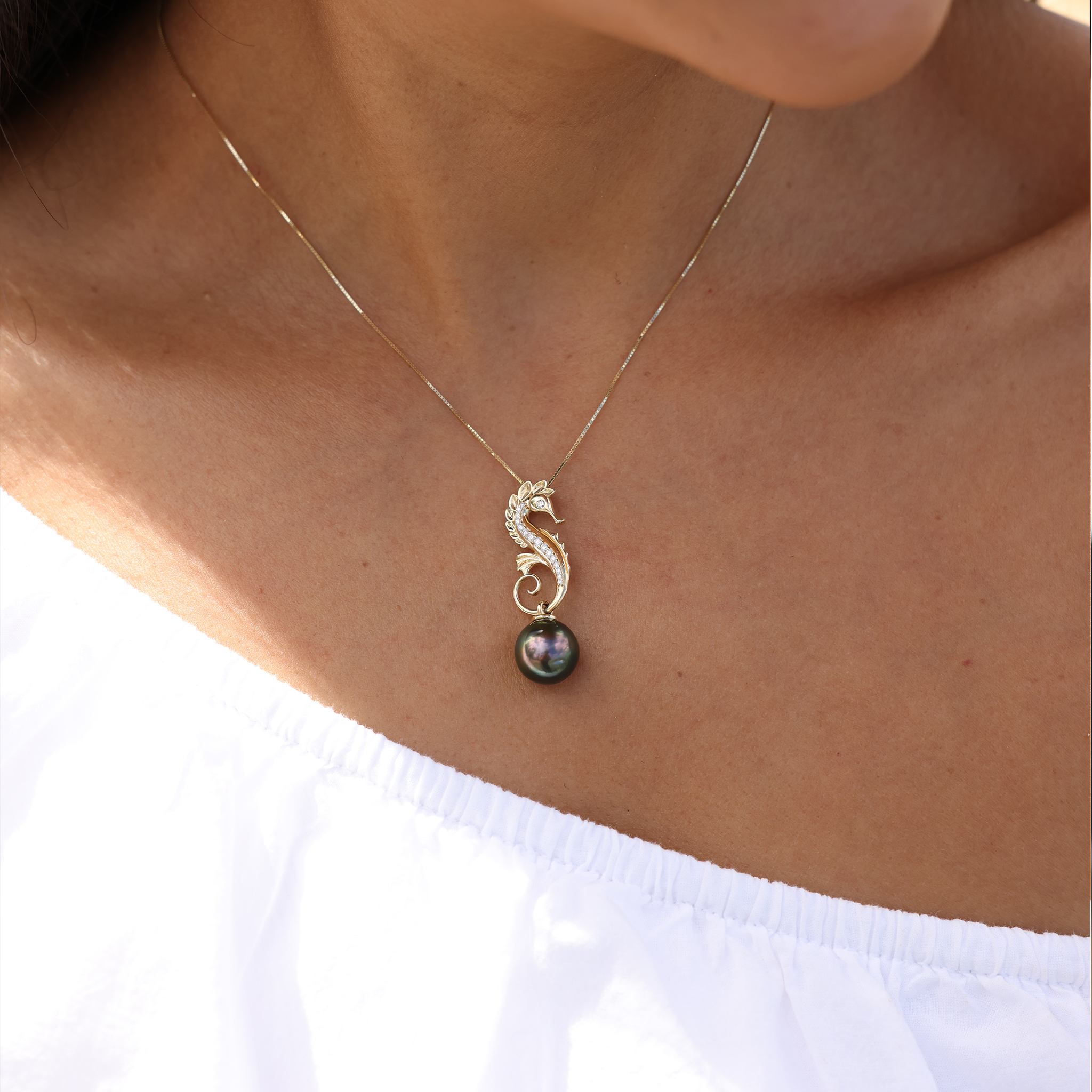 A womanʻs chest with an Ocean Dance Seahorse Tahitian Black Pearl Pendant in Gold with Diamonds - Maui Divers Jewelry