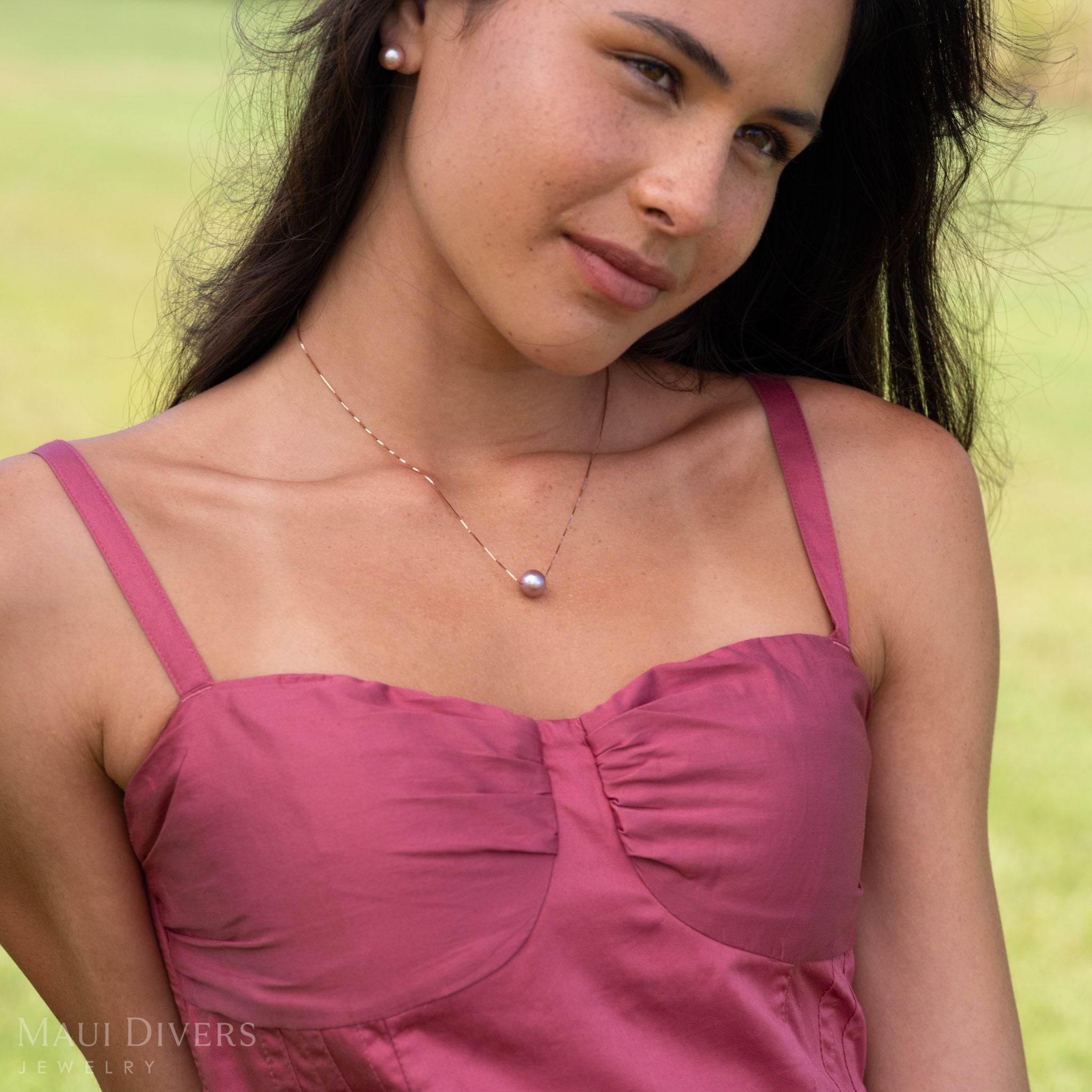 Woman looking outward wearing a Natural Freshwater Lilac Pearl Necklace with a 14k Rose Gold Chain and a pink dress. 