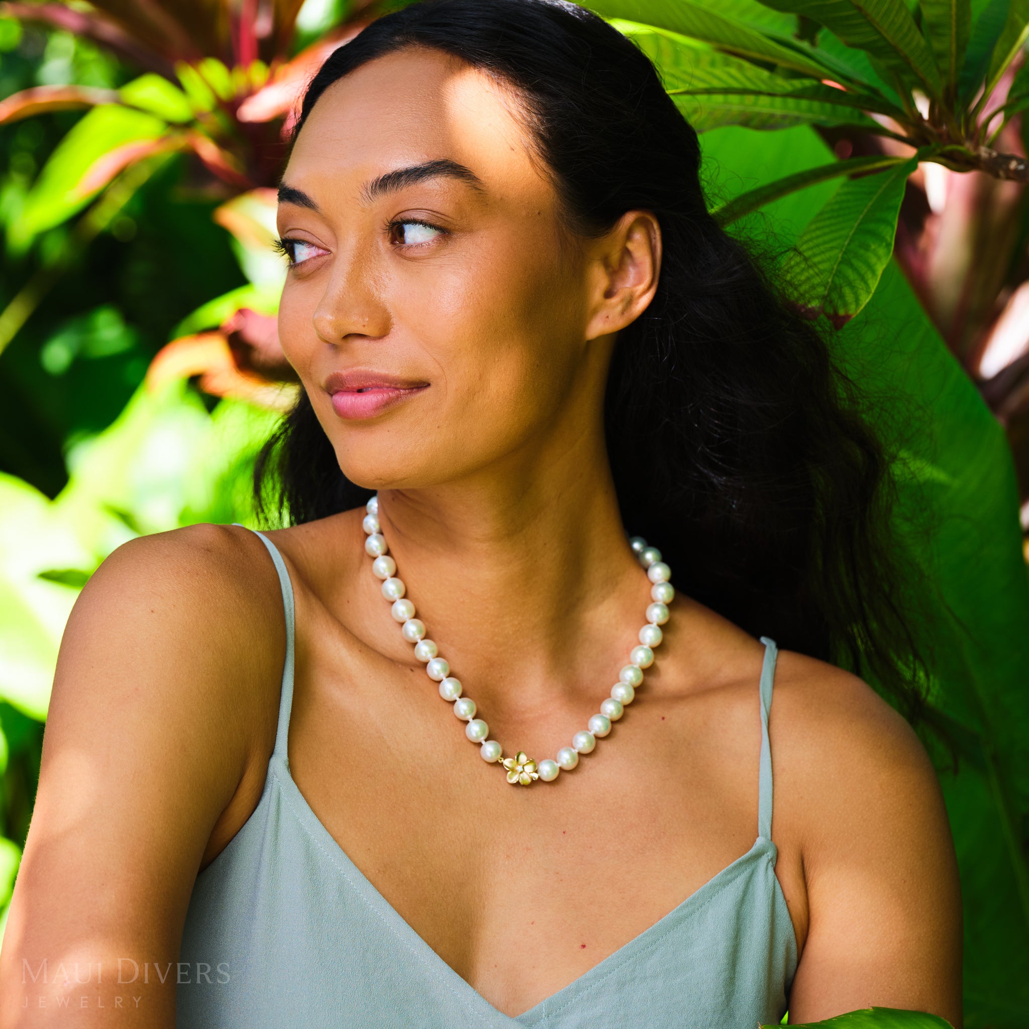 Woman with plants in background wearing a white pearl strand
