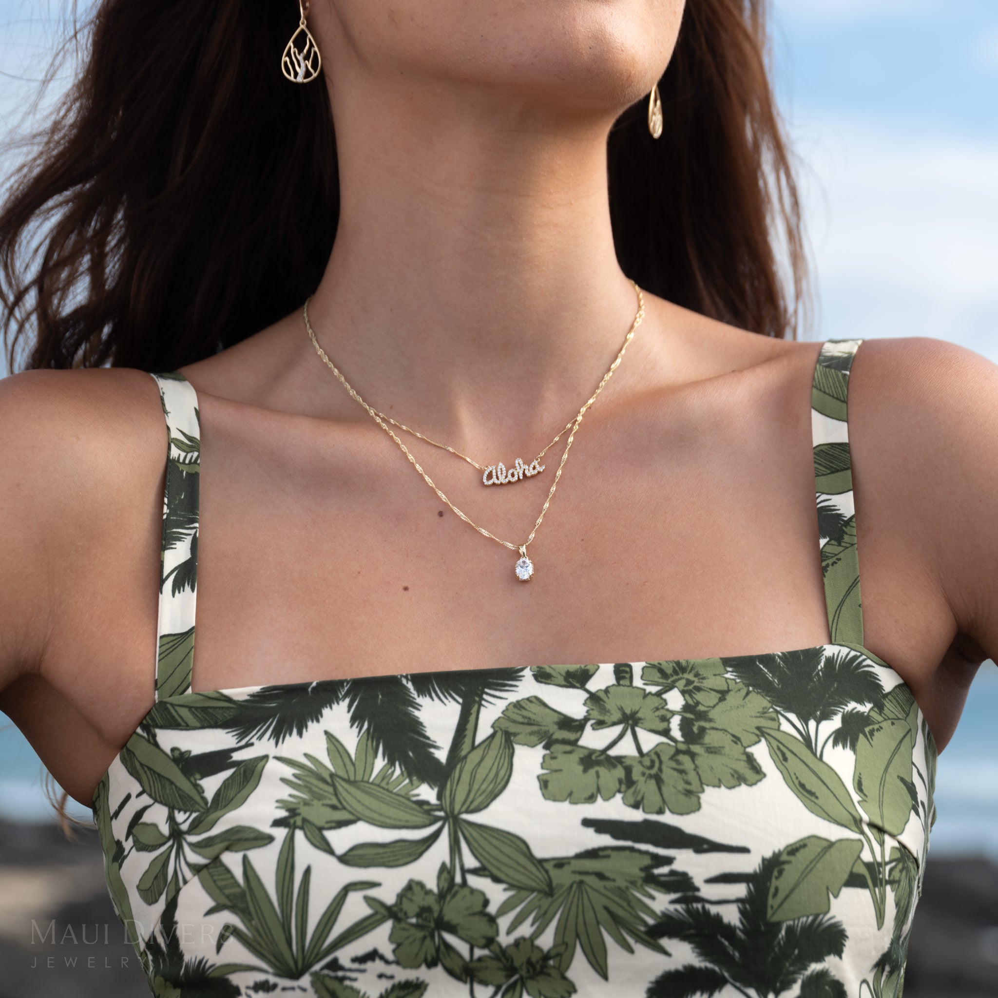 Close-up of a woman wearing a lab-grown diamond pendant on a Singapore chain and a diamond Aloha necklace 