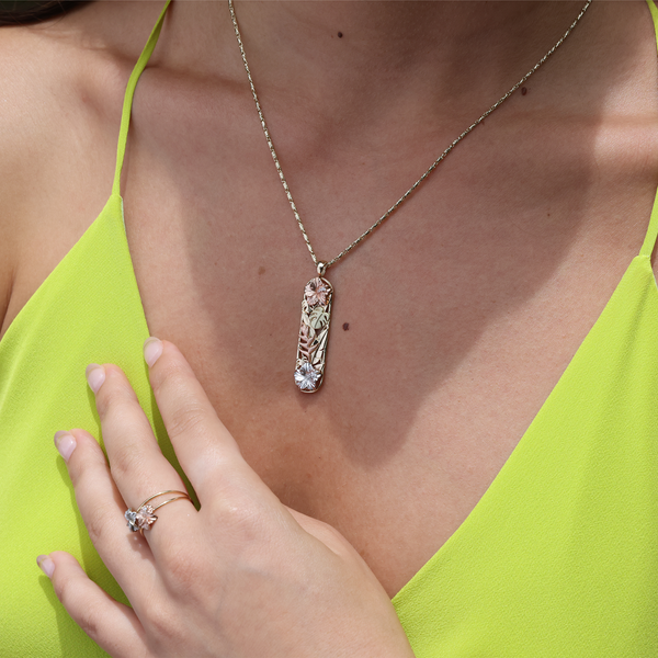 A woman wearing a Hawaiian Gardens Hibiscus Pendant in Multi Color Gold with Diamonds - 39mm - Maui Divers Jewelry