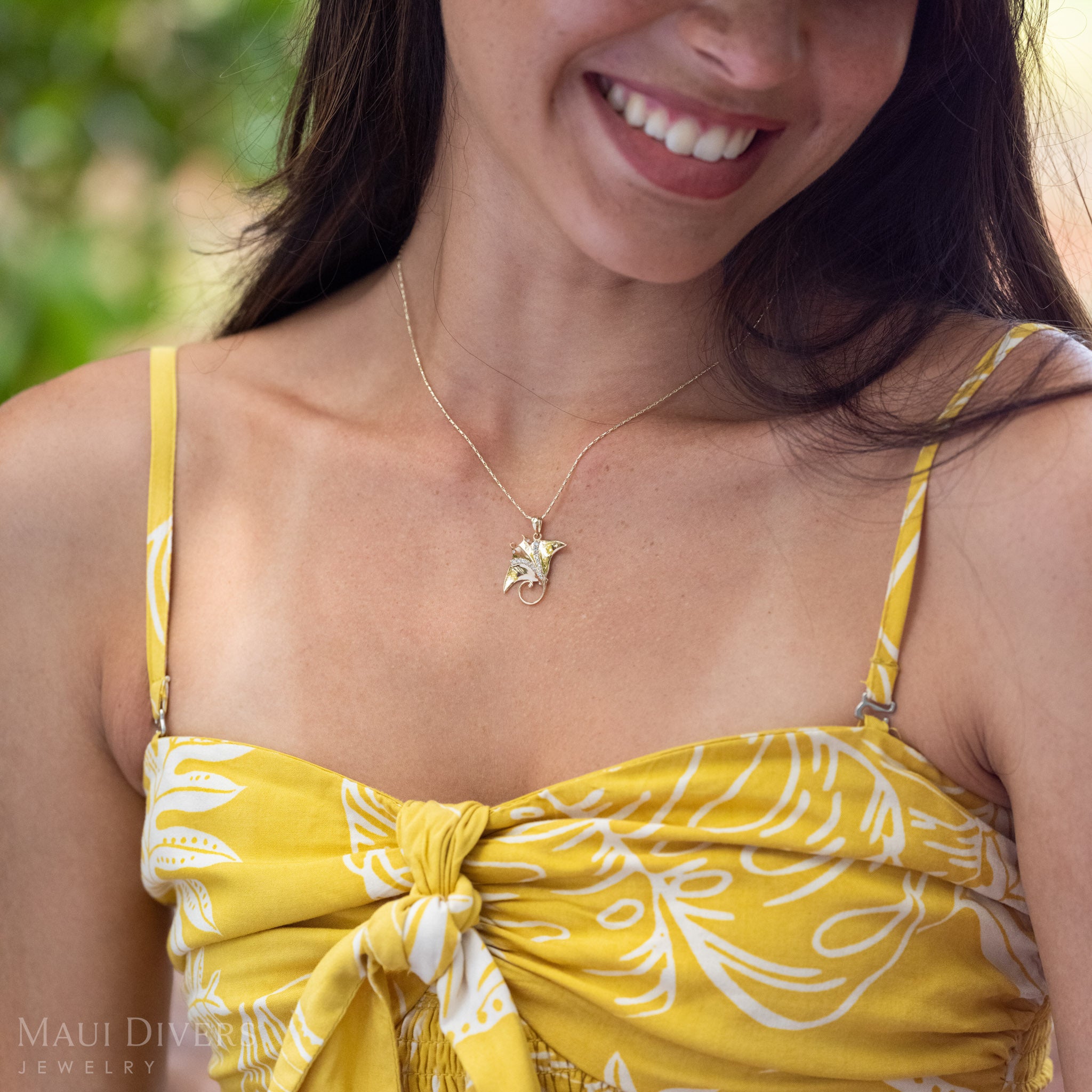Woman smiling wearing a 14k Gold Manta Ray Pendant around her neck with Natural Diamond detailing.