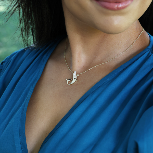 A woman's chest with an Ocean Dance Whale Pendant in Gold with Diamonds - 22mm - Maui Divers Jewelry
