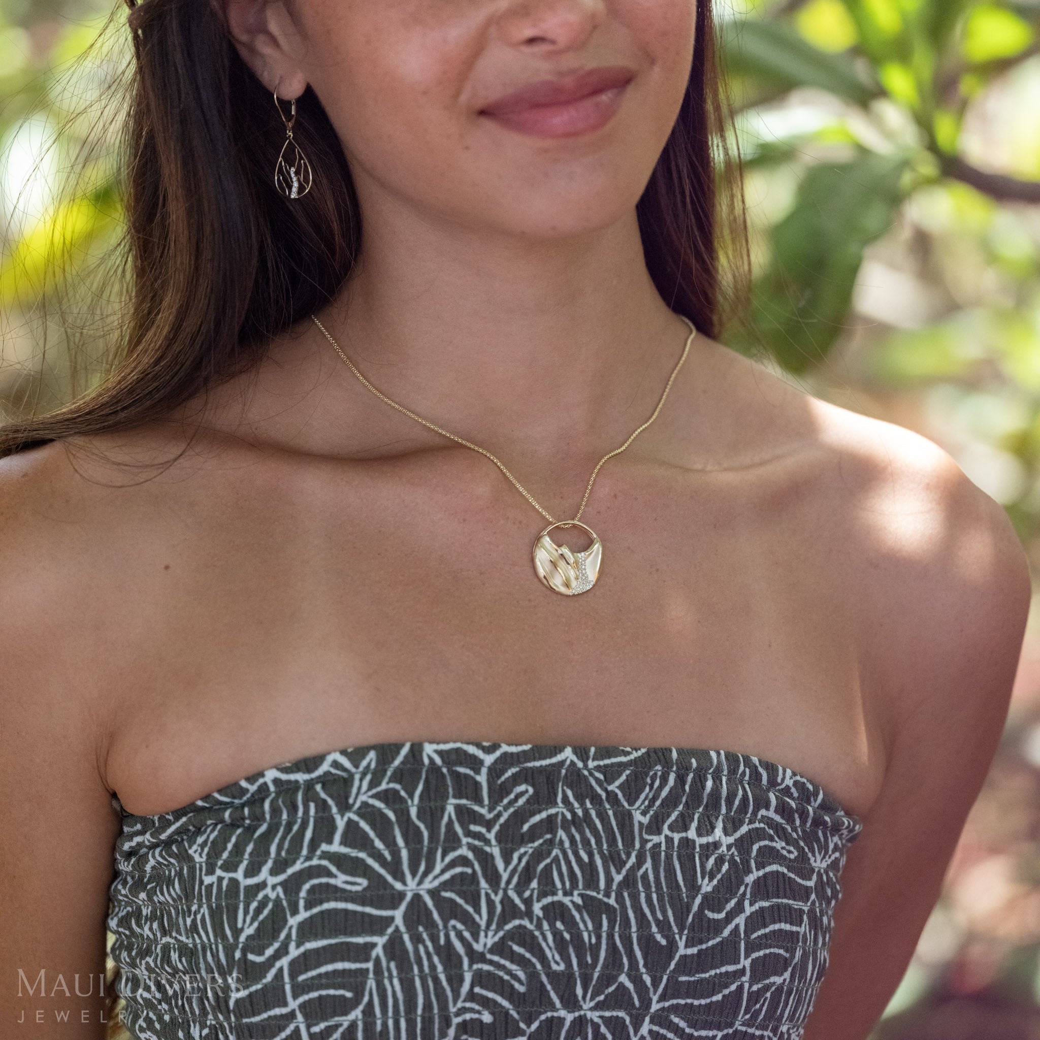 Close-up of a woman wearing a round 14k Gold Ko'olau Waterfall Pendant with Natural Diamonds and matching earrings. 