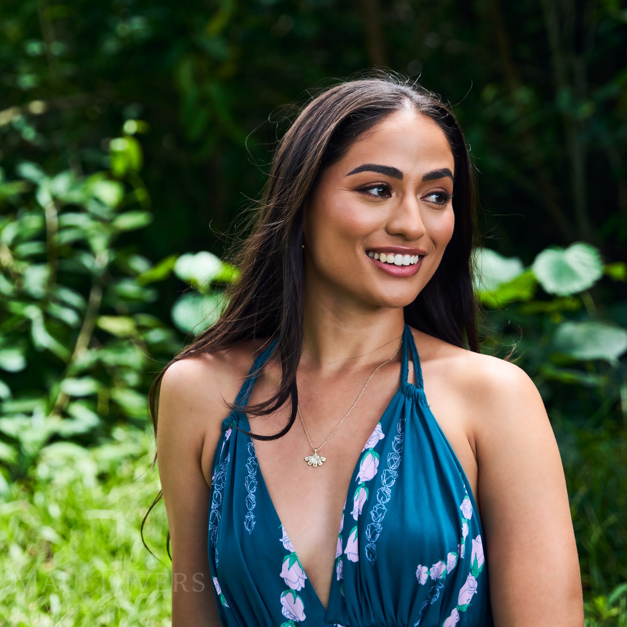 Woman in a tropical garden wearing a Beach Naupaka Pendant in Gold with Diamonds