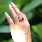 Woman wearing Maile Black Coral Ring in Gold with Diamonds - 7mm while touching leaf