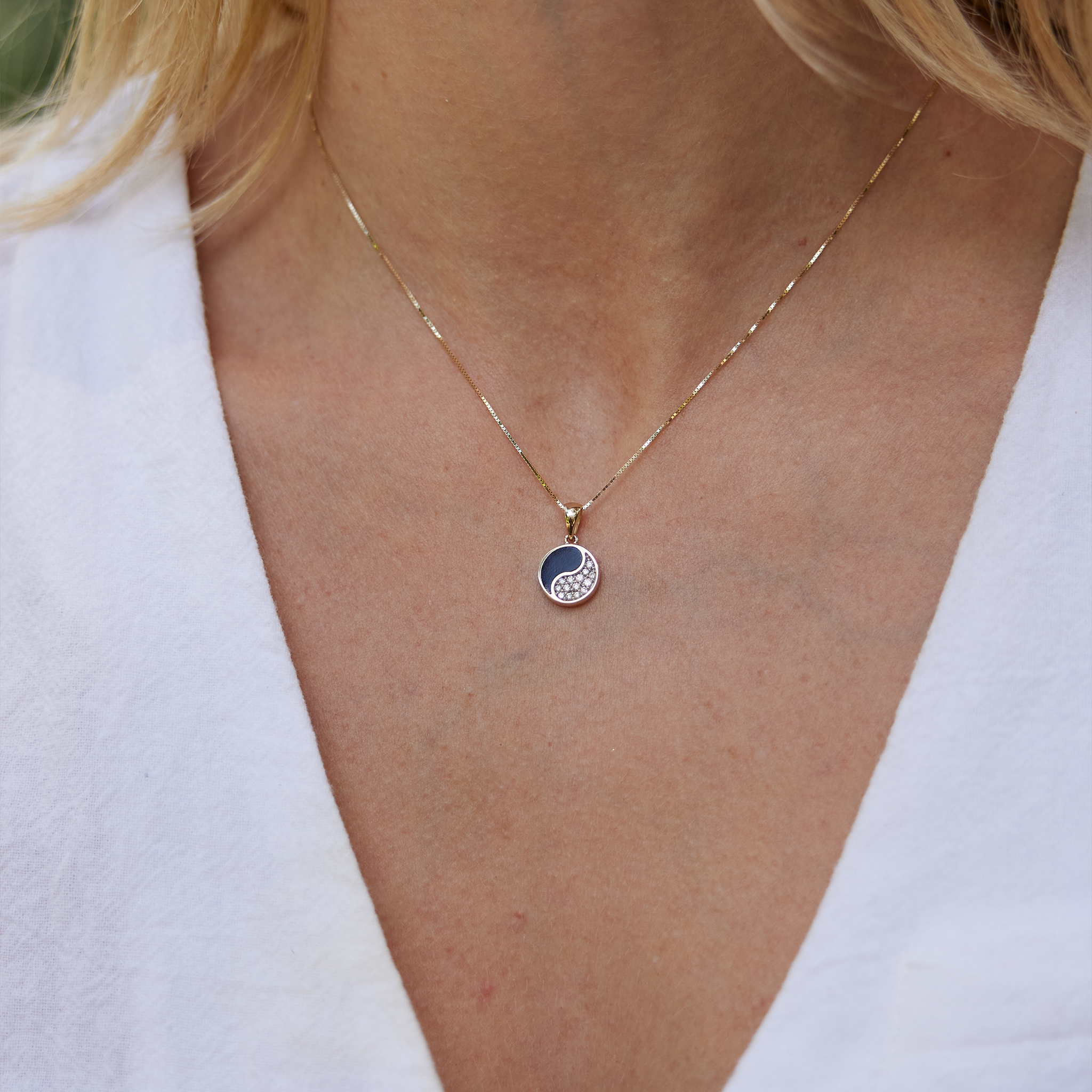 Close up of Yin Yang Black Coral Pendant in Gold with Diamonds - 10mm on womanʻs neckline