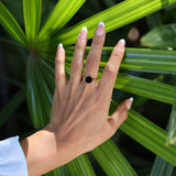Woman wearing Eclipse Flipside Black Coral Ring in Gold - 9mm with palm tree background