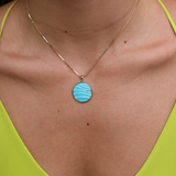 A woman's chest wearing a Hawaiian Moments Ocean Sand Pendant in Gold with Turquoise - 22mm - Maui Divers Jewelry