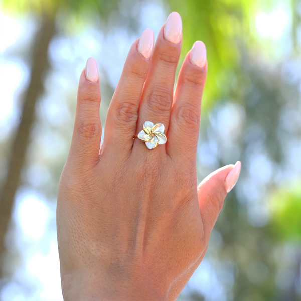 A woman's hand wearing a Plumeria Mother of Pearl Ring in Gold - Maui Divers Jewelry
