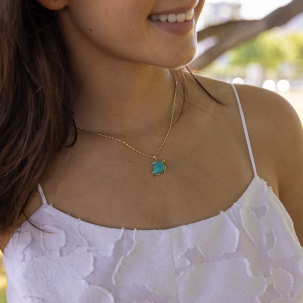A woman's chest with a Honu Turquoise Pendant in Gold - 16mm - Maui Divers Jewelry