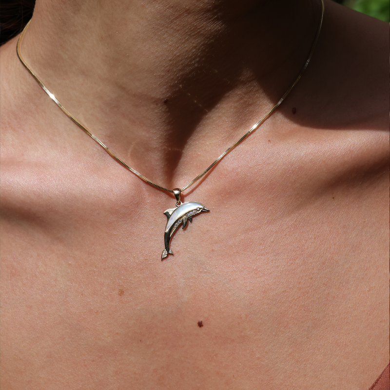 A woman's chest with a Sealife Dolphin Mother of PEarl Pendant in Gold with Diamonds - Maui Divers Jewelry