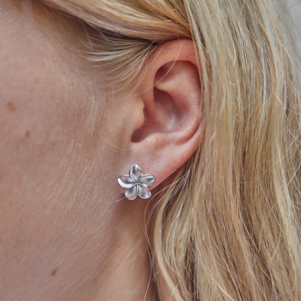 womanʻs ear showcasing Plumeria Earrings in Sterling Silver
