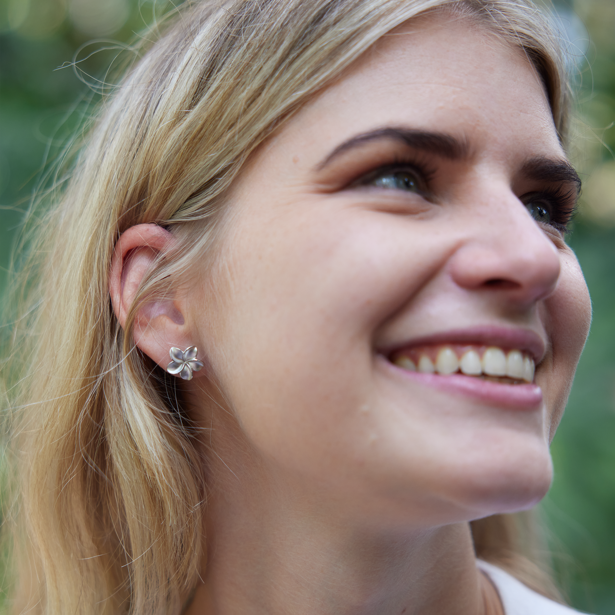 woman smiling with Plumeria Earrings in Sterling Silver - 13mm on right ear