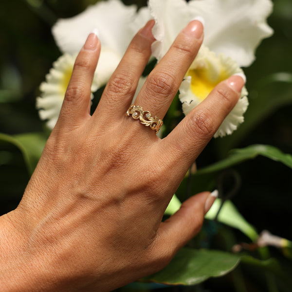 Close up of woman's hand wearing Living Heirloom Ring in Gold with Diamonds with tropical white flowers