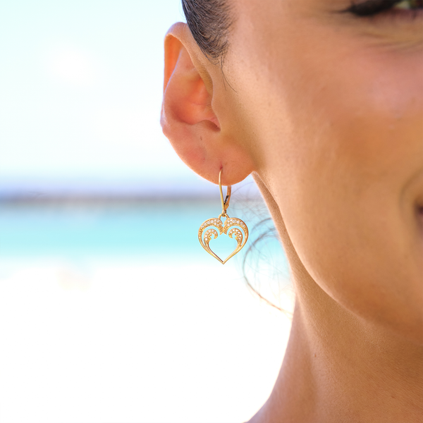 A womanʻs ear with Nalu Heart Earrings in Gold with Diamonds - 15mm - Maui Divers Jewelry