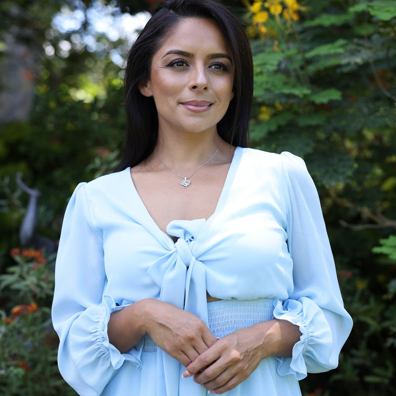 Woman with blue dress wearing Aloha Heart Pendant in White Gold with Diamonds - 18mm in Hawaiian botanical garden