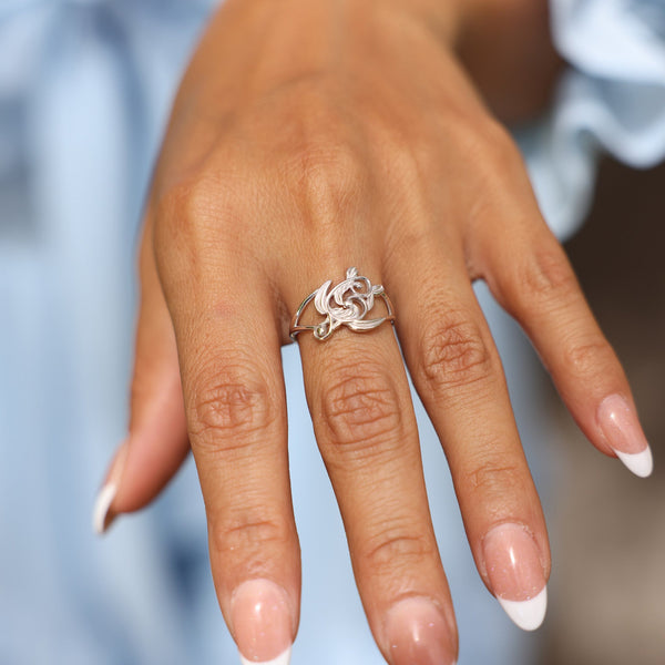 Close up of woman wearing Living Heirloom Honu Ring White Gold with blue background