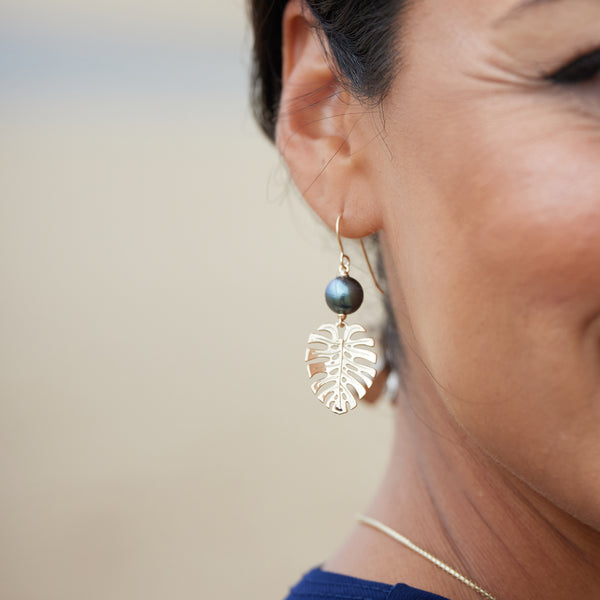 A woman's ear with Monstera Tahitian Black Pearl Earrings in Gold - 23mm - Maui Divers Jewelry