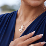 A woman's chest with a Monstera Pendant in Rose Gold with Diamonds - Maui Divers Jewelry 