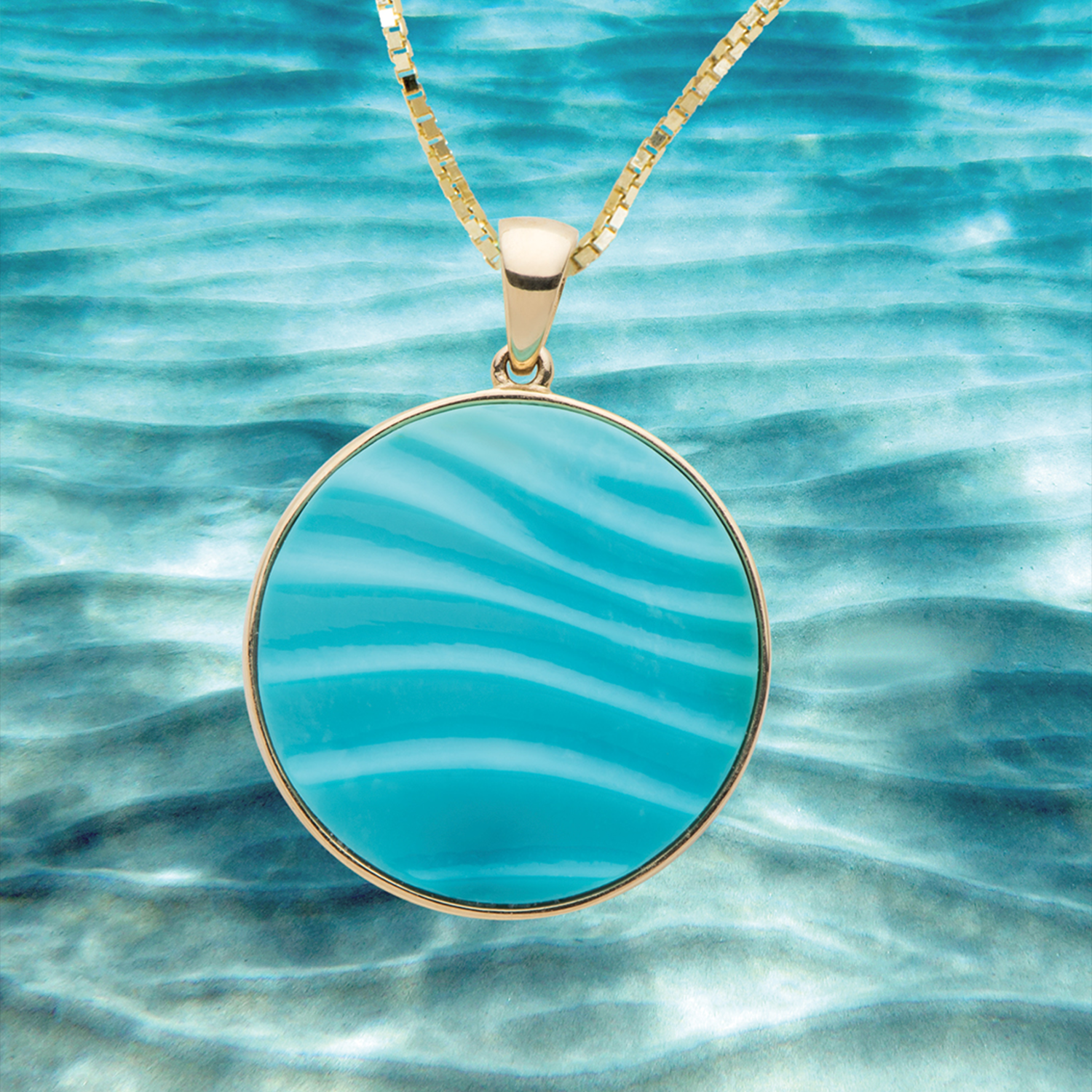 Turquoise Ocean Sand Pendant on a Box Chain with a rippled ocean sand floor in the background 