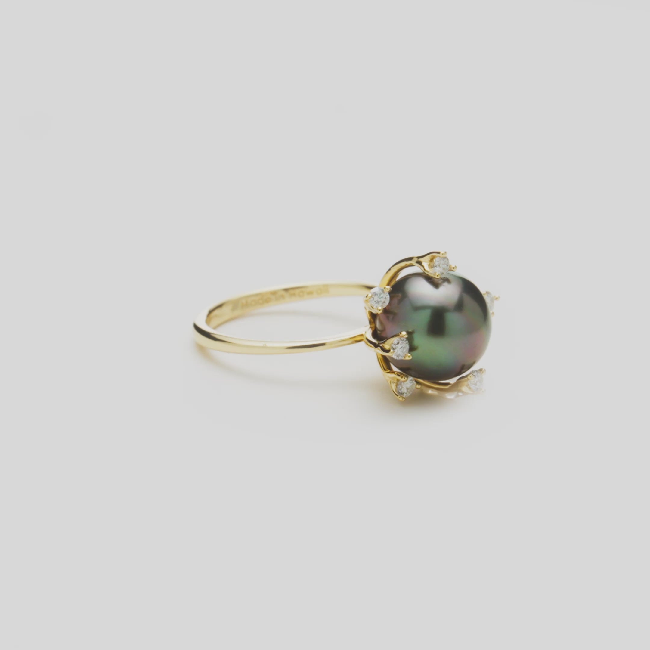 Close-up rotating video of a Tahitian black pearl ring with diamonds in 14k yellow gold against a white background