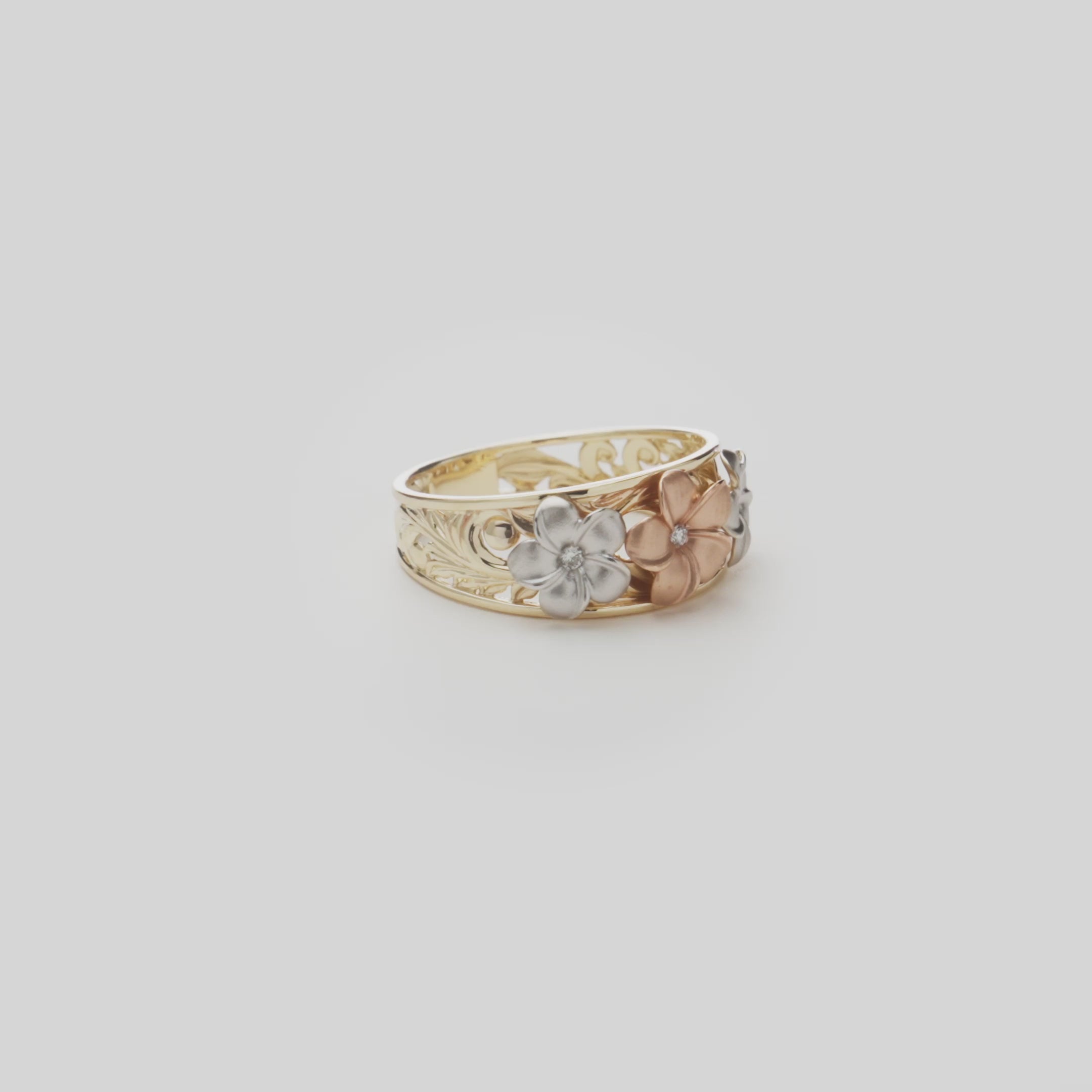 Hawaiian Heirloom Plumeria Ring in Tri Color Gold with Diamonds on a white turntable