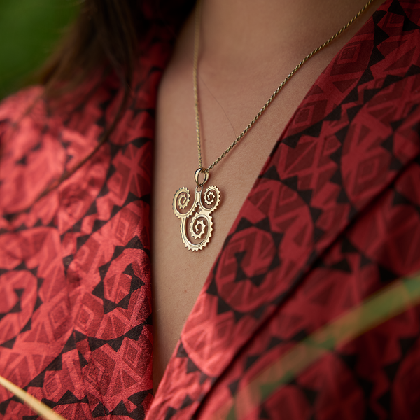 A woman's chest with a Kamohoaliʻi Kiha Pendant in Gold - 29mm - Maui Divers Jewelry