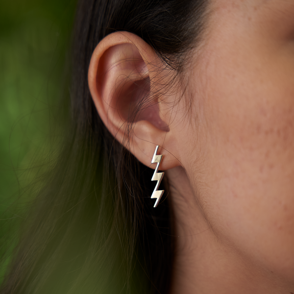 A woman's ear with Kamohoaliʻi Lightning bolt Earrings in Gold - 27.5mm - Maui Divers Jewelry