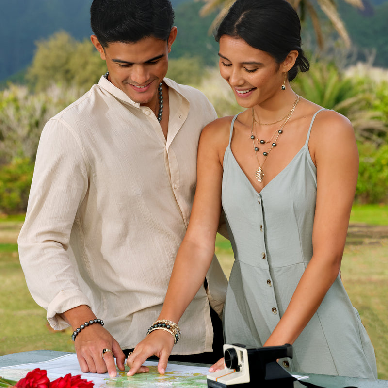 A couple pointing at a map, wearing a Montera Pendant in Gold with diamonds - 30mm- and other jewelry - Maui Divrs Jewelry