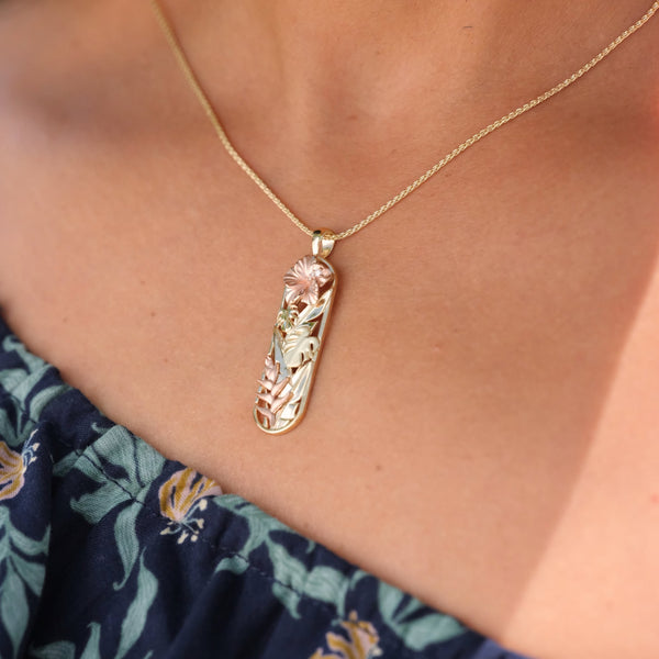 A woman's neck with a Hawaiian Gardens Hibiscus Pendant in Tri Color with Diamonds -32mm - Maui Divers Jewelry