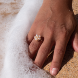 A woman's hand in the sand wearing a Tiny Bubbles Peach Freshwater Pearl Ring in Gold with Diamonds - Maui Divers Jewelry