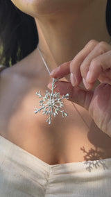 A video of a woman wearing a 2022 Limited Edition Hawaiian Snowflake Ornament in Sterling Silver - Maui Divers Jewelry