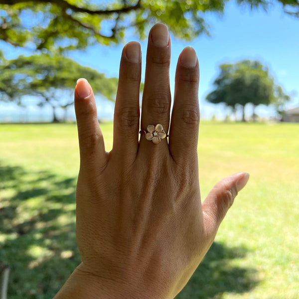 Rose Gold Plumeria Ring on Middle Finger over Nature Background
