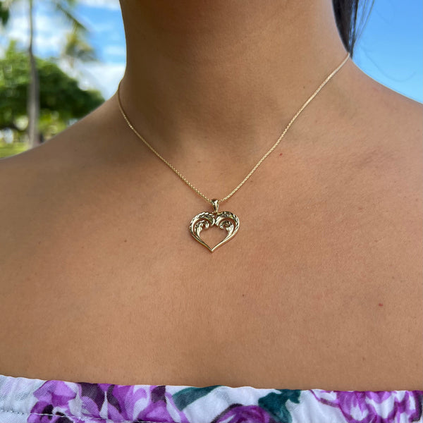 A woman's chest with a Nalu Heart Pendant in Gold - 20mm - Maui Divers Jewelry